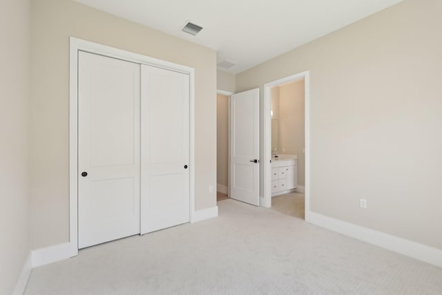 unfurnished bedroom with light carpet, baseboards, a closet, and ensuite bathroom