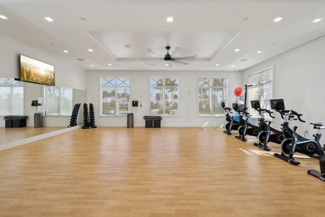 workout area featuring a tray ceiling, light wood-style floors, recessed lighting, and ceiling fan