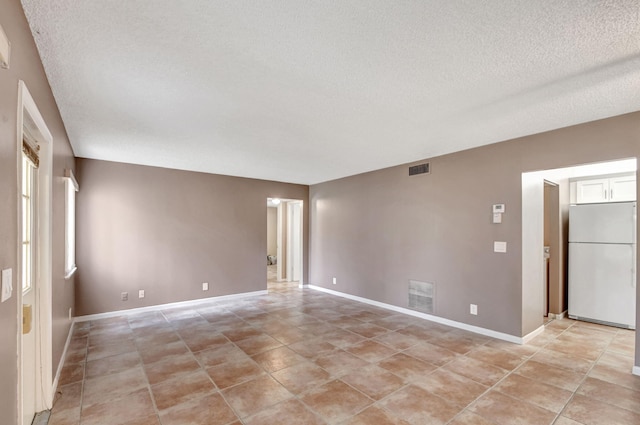 unfurnished room featuring a textured ceiling, baseboards, and light tile patterned floors
