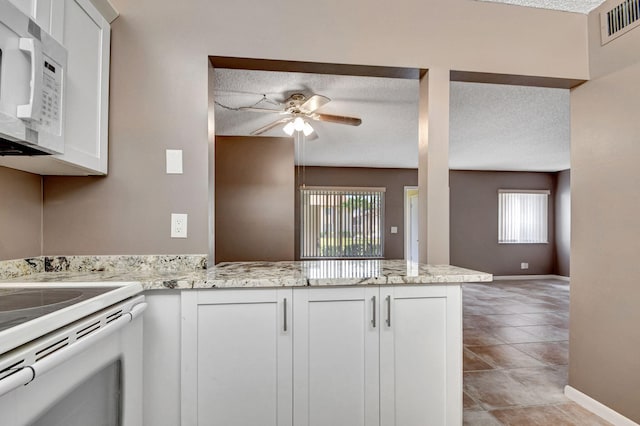 kitchen featuring white appliances, ceiling fan, baseboards, a peninsula, and white cabinetry