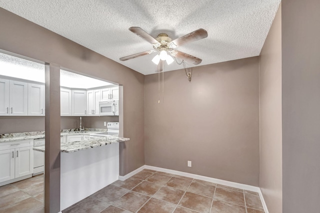 kitchen with white appliances, a textured ceiling, a ceiling fan, white cabinetry, and light stone countertops