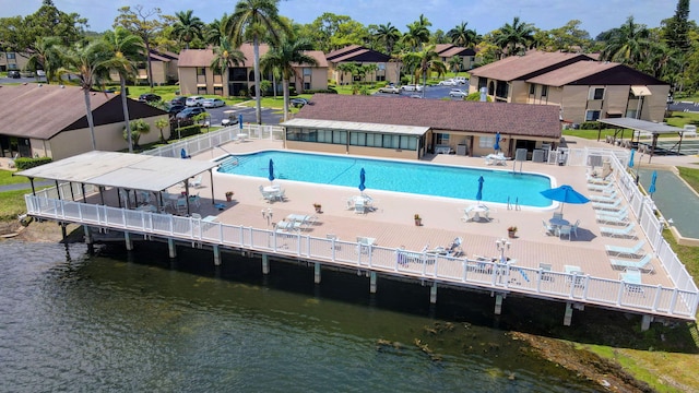 community pool with a water view, fence, and a residential view