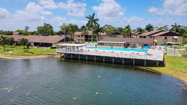 exterior space featuring a community pool, a water view, and fence