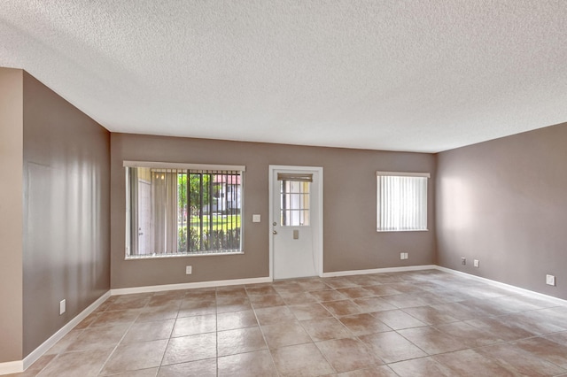 entrance foyer featuring a textured ceiling, light tile patterned floors, and baseboards
