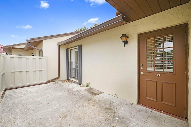 1017 Green Pine Blvd E, West Palm Beach, FL 33409 - view of exterior entry featuring stucco siding, a patio area, and fence
