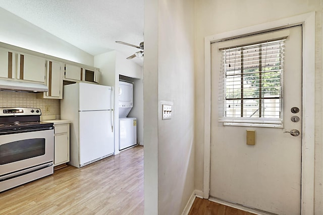 1017 Green Pine Blvd E, West Palm Beach, FL 33409 - kitchen featuring stainless steel electric stove, stacked washer / dryer, freestanding refrigerator, vaulted ceiling, and decorative backsplash