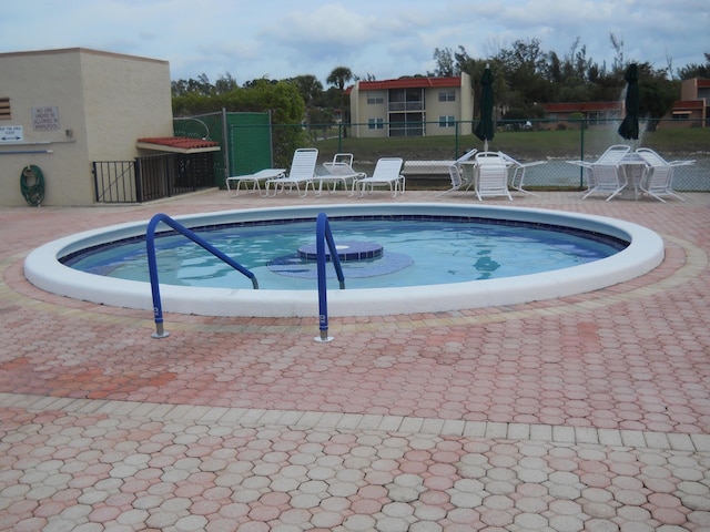 community pool with fence and a patio area