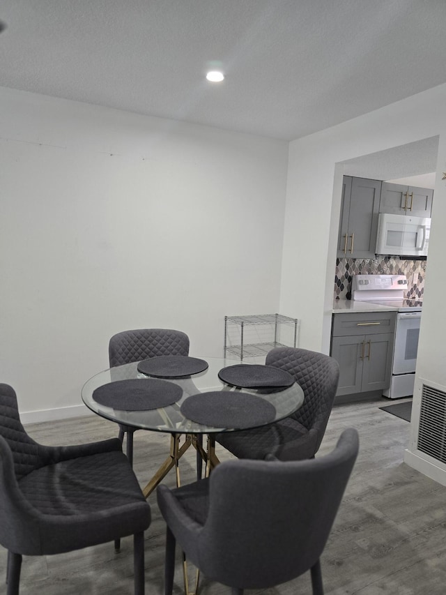 dining area featuring light wood-type flooring, wet bar, and baseboards
