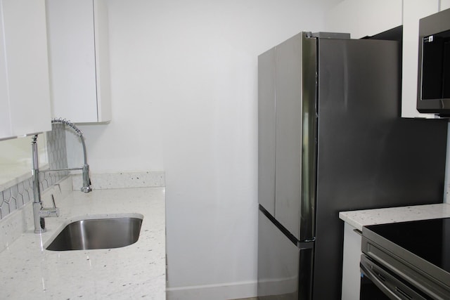 3264 Ocean Pkwy, Boynton Beach, FL 33435 - kitchen featuring appliances with stainless steel finishes, white cabinetry, a sink, and light stone countertops