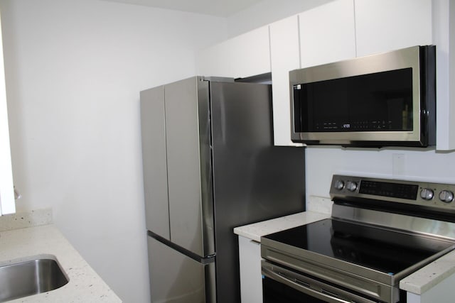 3264 Ocean Pkwy, Boynton Beach, FL 33435 - kitchen with appliances with stainless steel finishes, white cabinets, light stone counters, and a sink