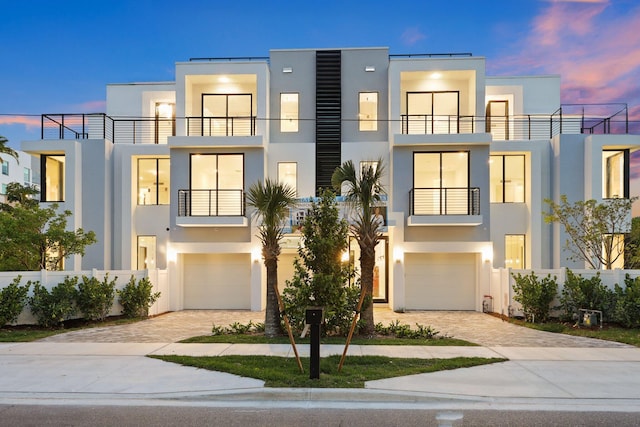 modern home featuring stucco siding, decorative driveway, and an attached garage