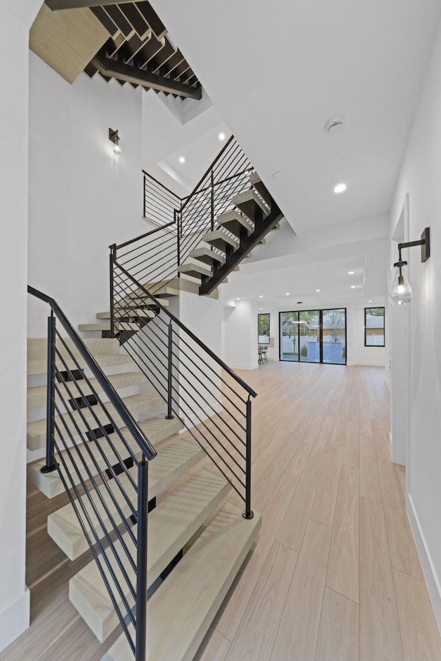 stairs featuring wood finished floors, recessed lighting, and baseboards