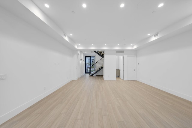 unfurnished living room featuring recessed lighting, stairs, light wood-type flooring, and baseboards