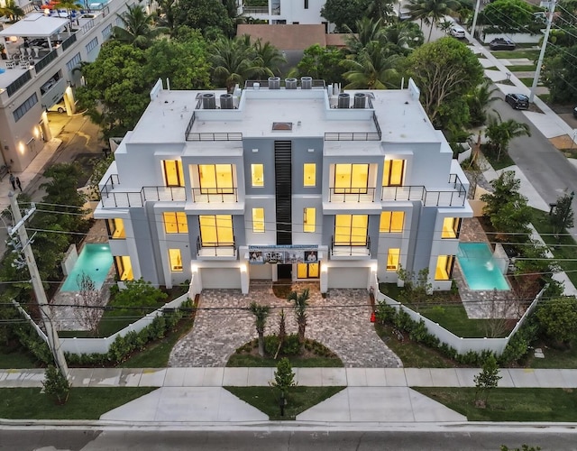 rear view of property with a balcony, stucco siding, decorative driveway, and an attached garage