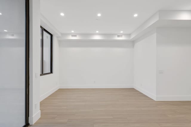 spare room featuring light wood-style floors, baseboards, and recessed lighting