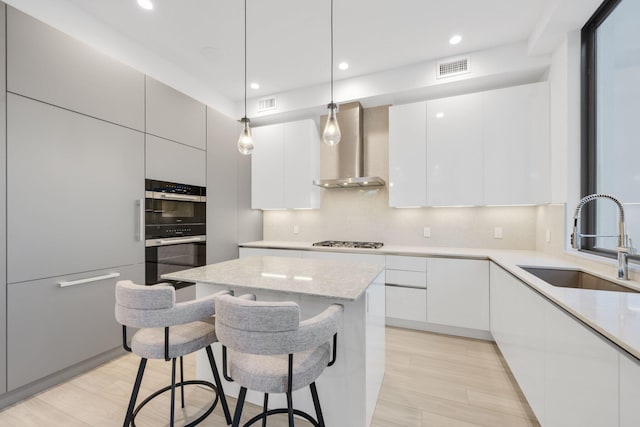 kitchen with wall chimney range hood, a sink, modern cabinets, appliances with stainless steel finishes, and recessed lighting