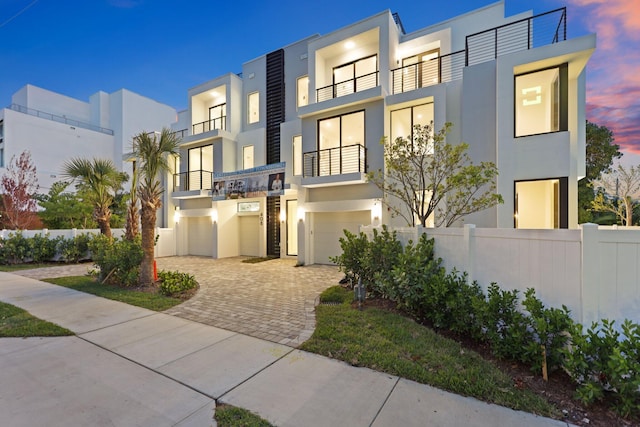 contemporary home with stucco siding, an attached garage, driveway, and a balcony
