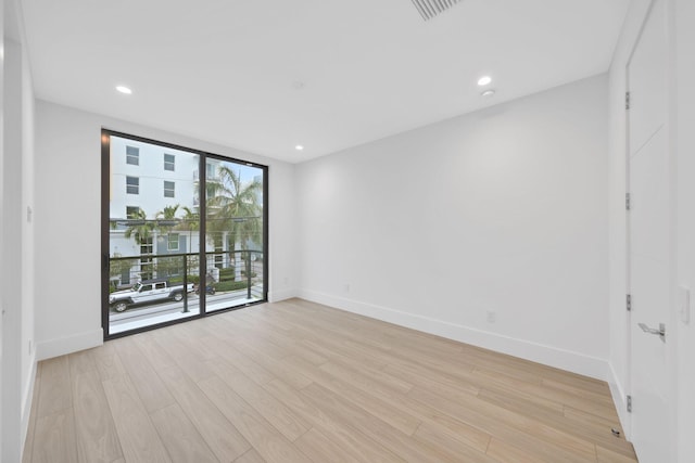 unfurnished room with light wood-type flooring, baseboards, floor to ceiling windows, and recessed lighting