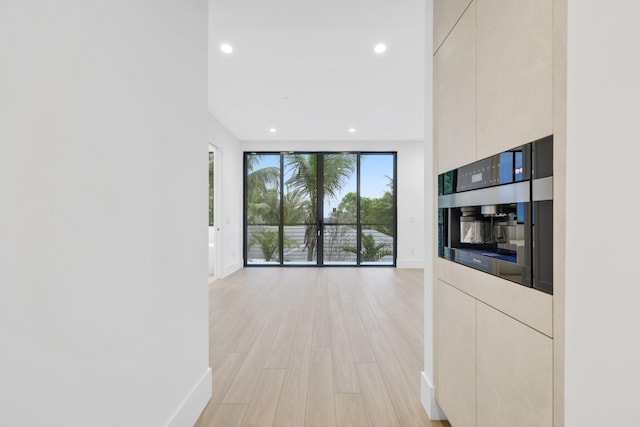 corridor featuring baseboards, recessed lighting, and light wood finished floors
