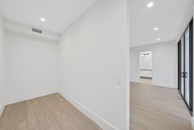 corridor featuring light wood-style flooring, baseboards, and recessed lighting