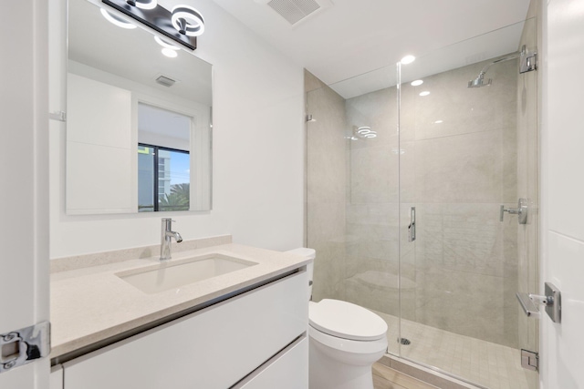 bathroom featuring toilet, vanity, a stall shower, and recessed lighting
