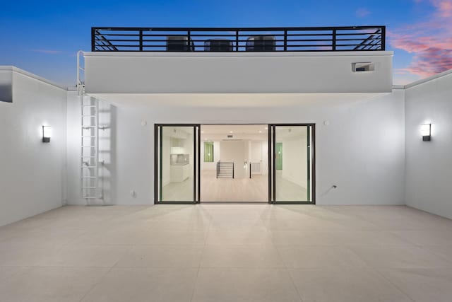 back of house at dusk with a patio and stucco siding