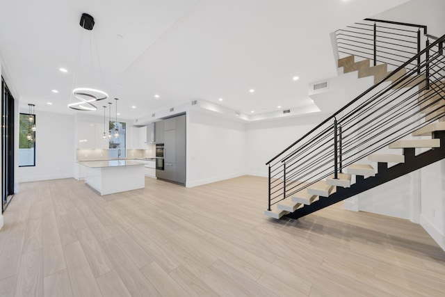 201 SE 4th Ave, Delray Beach, FL 33483 - unfurnished living room with baseboards, a chandelier, stairway, light wood finished floors, and recessed lighting