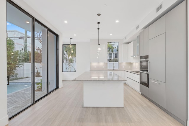 201 SE 4th Ave, Delray Beach, FL 33483 - kitchen featuring modern cabinets, a center island, white cabinetry, pendant lighting, and backsplash