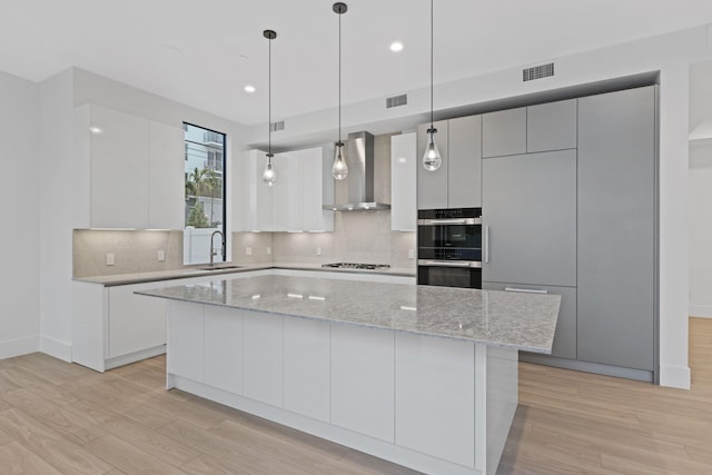 201 SE 4th Ave, Delray Beach, FL 33483 - kitchen with wall chimney exhaust hood, modern cabinets, light wood-type flooring, decorative backsplash, and recessed lighting