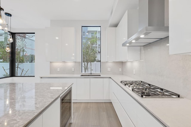 201 SE 4th Ave, Delray Beach, FL 33483 - kitchen with wall chimney range hood, modern cabinets, wine cooler, white cabinets, and stainless steel gas cooktop