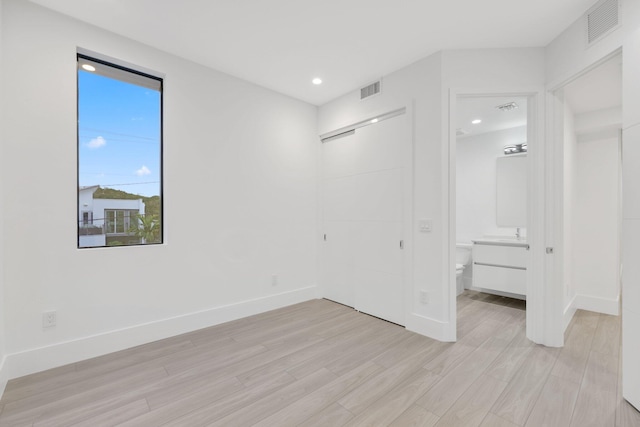 201 SE 4th Ave, Delray Beach, FL 33483 - unfurnished bedroom featuring light wood-style flooring, baseboards, ensuite bath, and recessed lighting