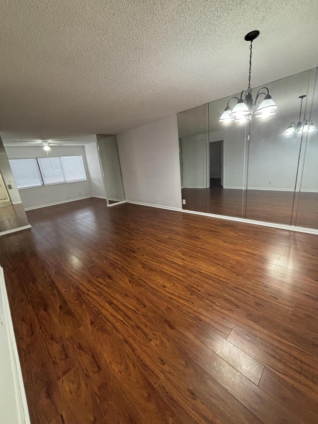 4820 Lucerne Lakes Blvd W Unit 107, Greenacres, FL 33467 - unfurnished living room featuring a textured ceiling, dark wood-type flooring, baseboards, a ceiling fan, and a chandelier