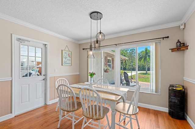 11447 Orange Grove Blvd, West Palm Beach, FL 33411 - dining area with light wood finished floors, a textured ceiling, ornamental molding, a wainscoted wall, and baseboards