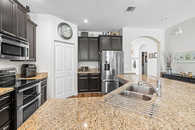 7267 Prudencia Dr, Lake Worth, FL 33463 - kitchen with stainless steel appliances, arched walkways, a sink, wood finished floors, and a textured ceiling