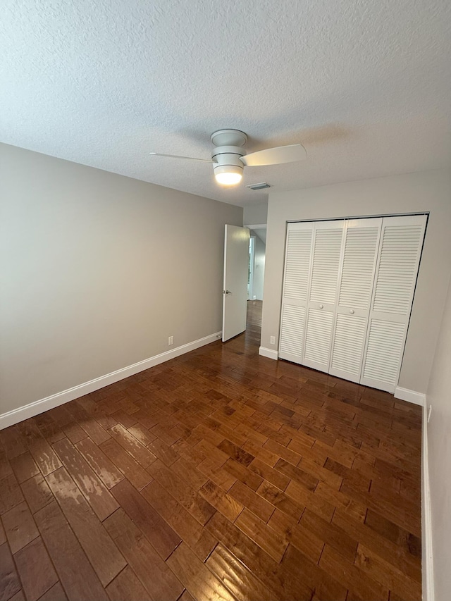 310 SE 2nd Ave Unit A3, Deerfield Beach, FL 33441 - unfurnished bedroom featuring dark wood-style flooring, a closet, a textured ceiling, a ceiling fan, and baseboards