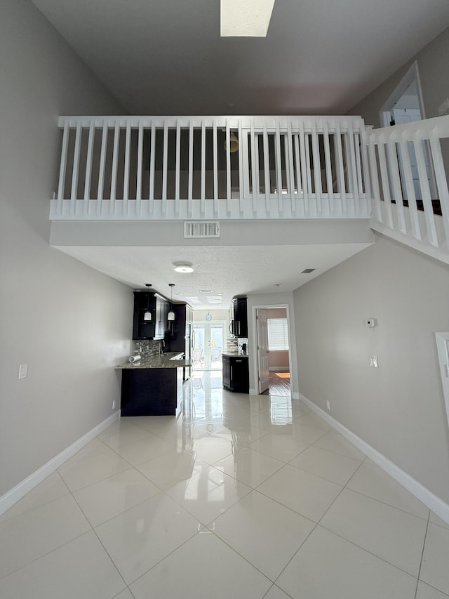 310 SE 2nd Ave Unit A3, Deerfield Beach, FL 33441 - unfurnished living room featuring baseboards, light tile patterned flooring, and a towering ceiling