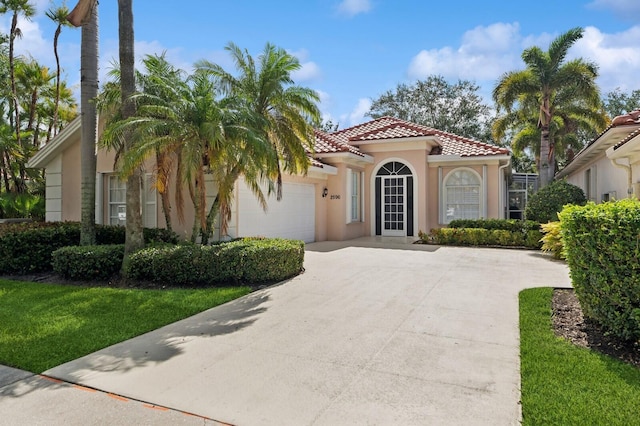 2596 Irma Lake Dr, West Palm Beach, FL 33411 - mediterranean / spanish-style house with a garage, a tile roof, concrete driveway, stucco siding, and a front yard
