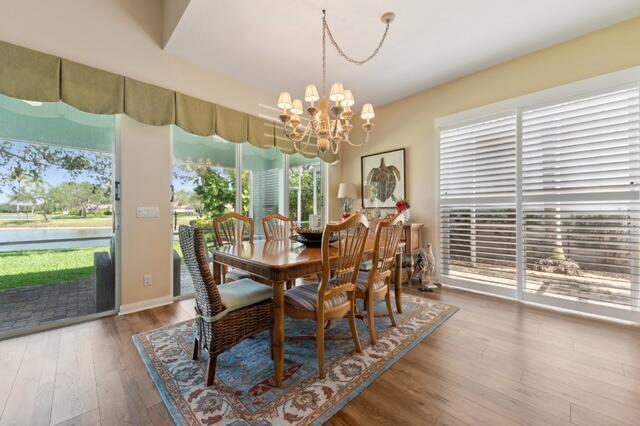 2596 Irma Lake Dr, West Palm Beach, FL 33411 - dining space featuring a chandelier, wood finished floors, plenty of natural light, and a water view