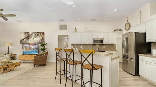6193 Winding Lake Dr, Jupiter, FL 33458 - kitchen featuring stainless steel appliances, light wood finished floors, tasteful backsplash, a kitchen island, and recessed lighting