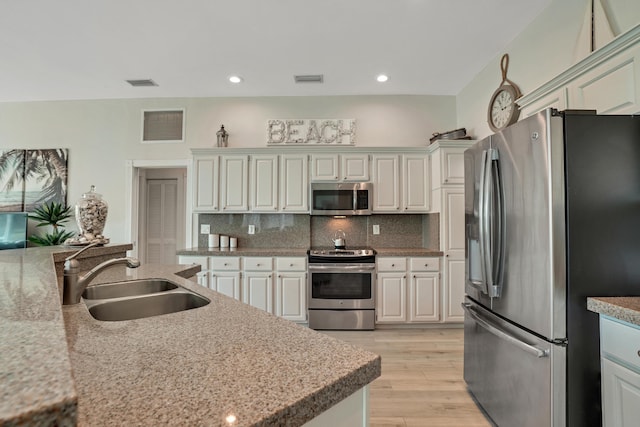 6193 Winding Lake Dr, Jupiter, FL 33458 - kitchen featuring stainless steel appliances, a sink, light wood-type flooring, tasteful backsplash, and light countertops