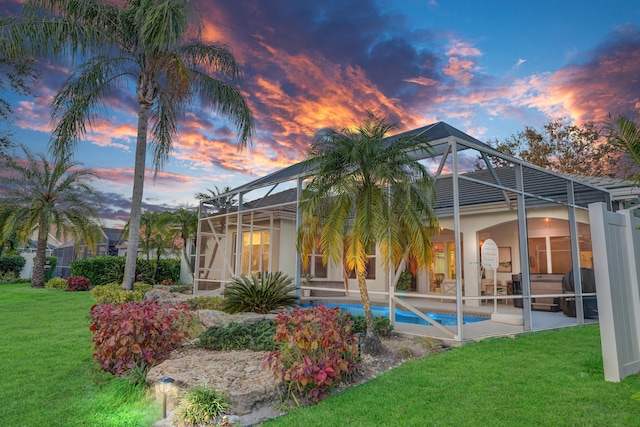 6193 Winding Lake Dr, Jupiter, FL 33458 - back of property at dusk with glass enclosure, stucco siding, a yard, an outdoor pool, and a patio area