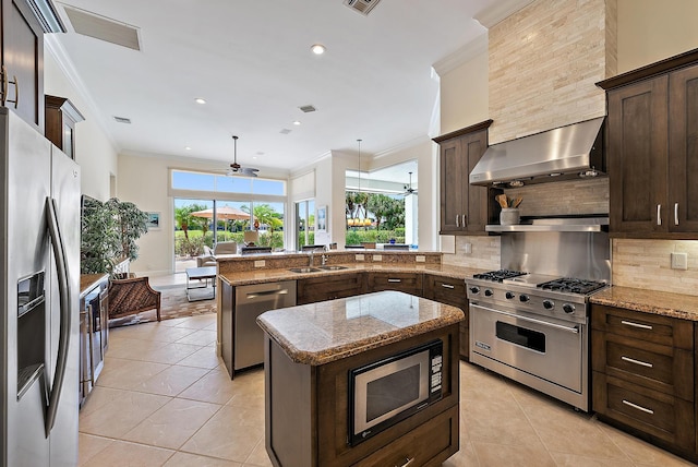 kitchen with appliances with stainless steel finishes, wall chimney range hood, a ceiling fan, a sink, and ornamental molding