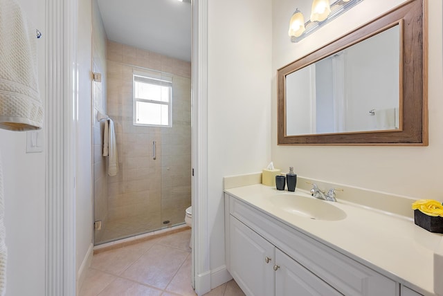 bathroom with toilet, tile patterned floors, vanity, a stall shower, and baseboards