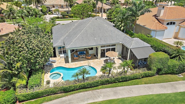 view of pool with a pool with connected hot tub, a residential view, a patio area, and a fenced backyard