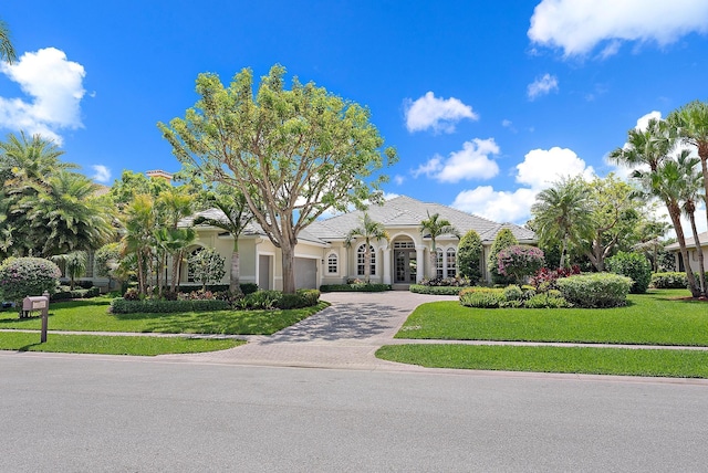 view of front of house with decorative driveway, a front yard, stucco siding, and french doors