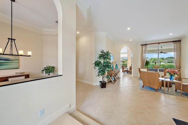 hall featuring arched walkways, crown molding, baseboards, recessed lighting, and light tile patterned floors