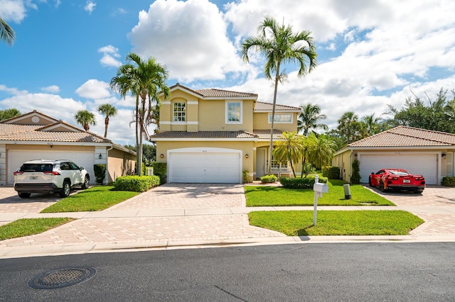 view of front of home featuring stucco siding, decorative driveway, a tiled roof, and a front yard