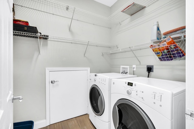 clothes washing area featuring washer and dryer, light wood-style floors, and baseboards