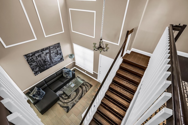staircase featuring wood finished floors, baseboards, and a chandelier