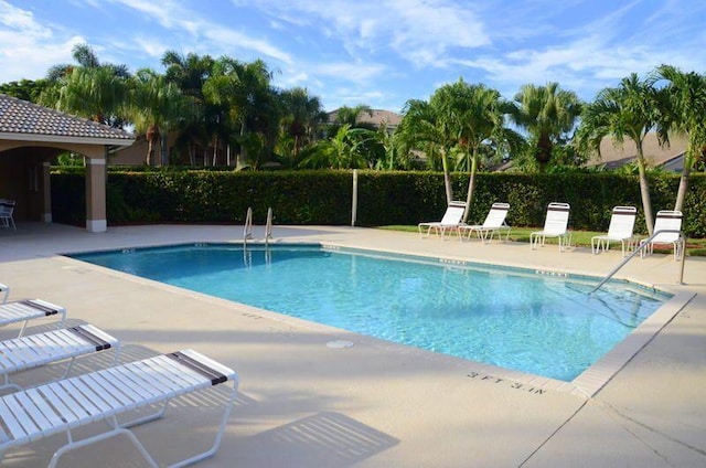 community pool with a patio and fence